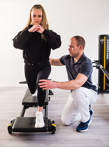 Physiotherapeut trainiert mit einer Patientin am Fitnessgerät